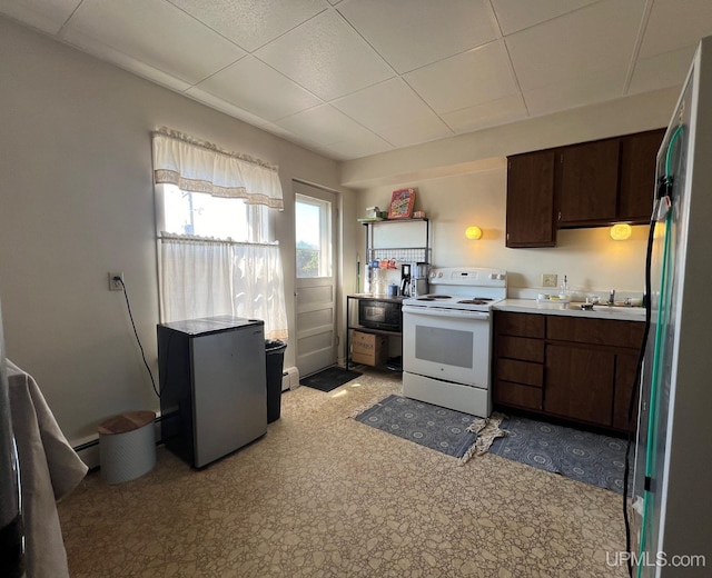 kitchen with stainless steel fridge, dark brown cabinetry, white electric stove, and a baseboard heating unit