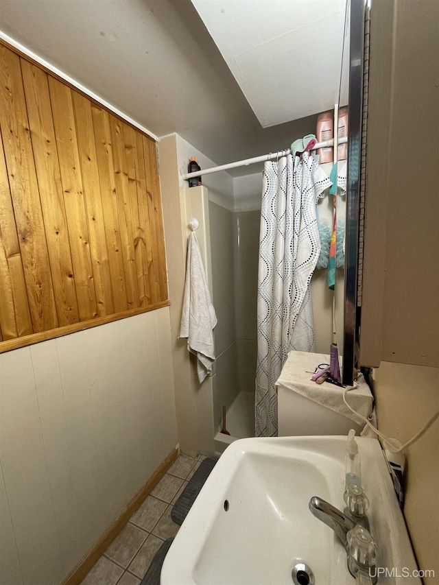 bathroom featuring a shower with curtain, tile patterned flooring, sink, and wood walls