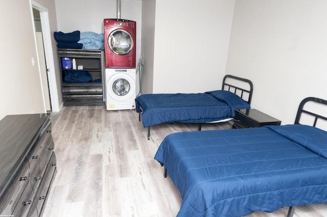 bedroom with light wood-type flooring and stacked washer / drying machine