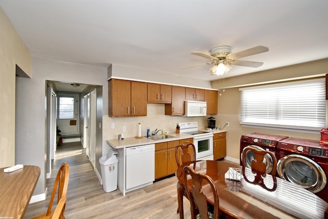 kitchen featuring ceiling fan, sink, washing machine and dryer, light hardwood / wood-style floors, and white appliances