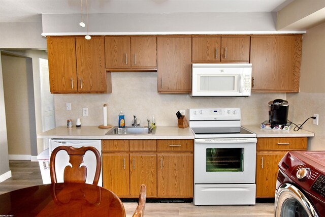 kitchen featuring white appliances, sink, washer / dryer, and light hardwood / wood-style floors