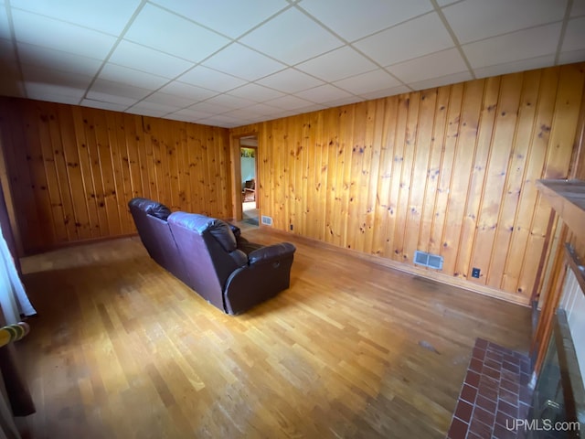 unfurnished room featuring wooden walls, a paneled ceiling, and hardwood / wood-style flooring