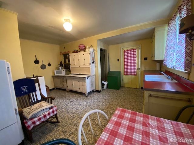 kitchen with sink, white cabinetry, and light colored carpet