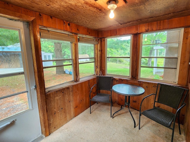 sunroom / solarium with wood ceiling, wood walls, and carpet
