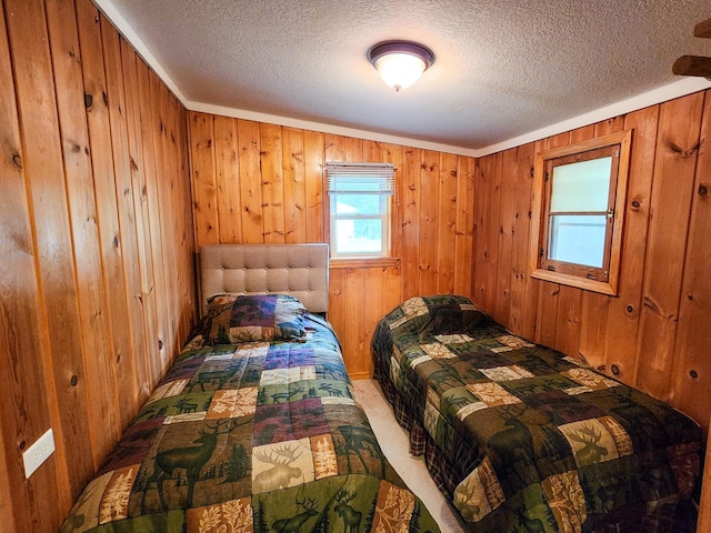 bedroom with carpet floors, a textured ceiling, and wood walls