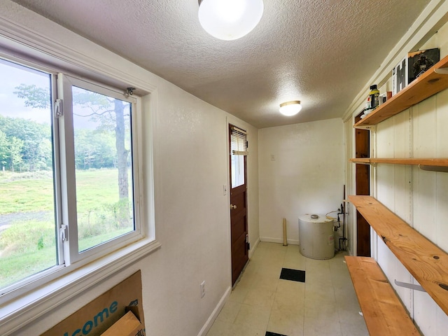 interior space with a textured ceiling, baseboards, and a healthy amount of sunlight