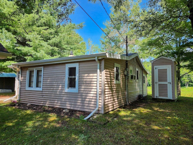 view of property exterior featuring a storage shed, a lawn, and an outdoor structure