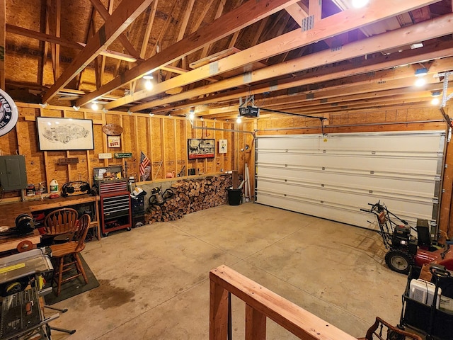 garage with electric panel, a workshop area, and a garage door opener