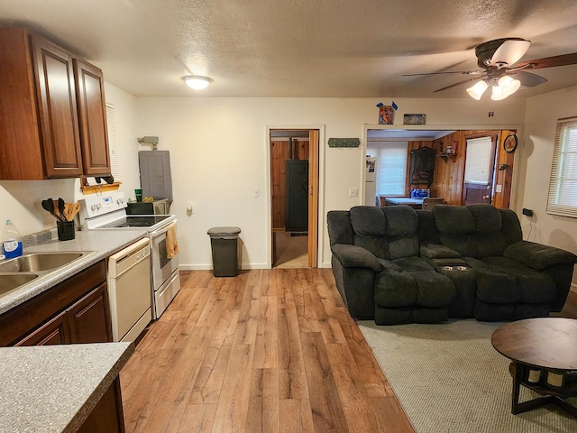 kitchen featuring white appliances, electric panel, light carpet, sink, and ceiling fan