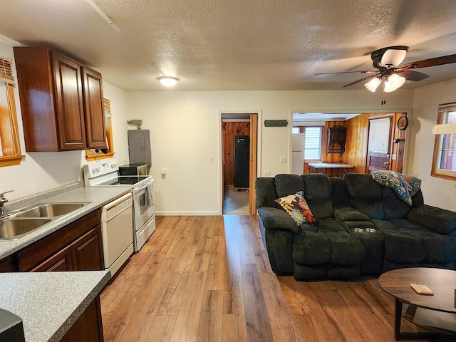 kitchen with light wood-style flooring, white appliances, a textured ceiling, and a sink