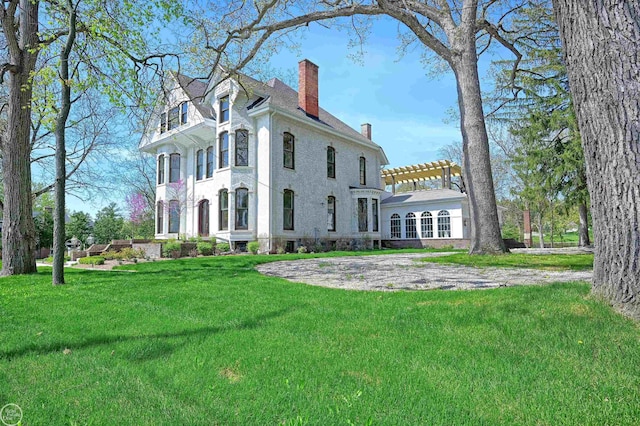 rear view of property with a pergola and a lawn