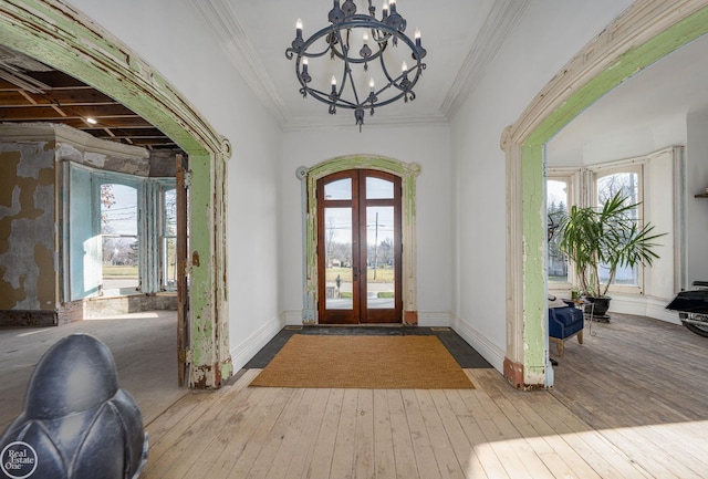 entrance foyer with a notable chandelier, light hardwood / wood-style flooring, french doors, and ornamental molding