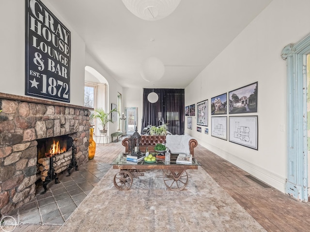 living room with a stone fireplace and wood-type flooring