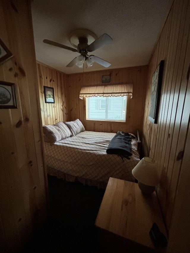 bedroom with ceiling fan and wooden walls