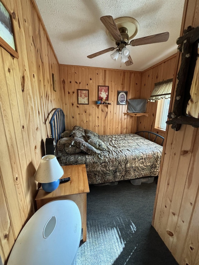 bedroom with ceiling fan, carpet floors, a textured ceiling, and wood walls