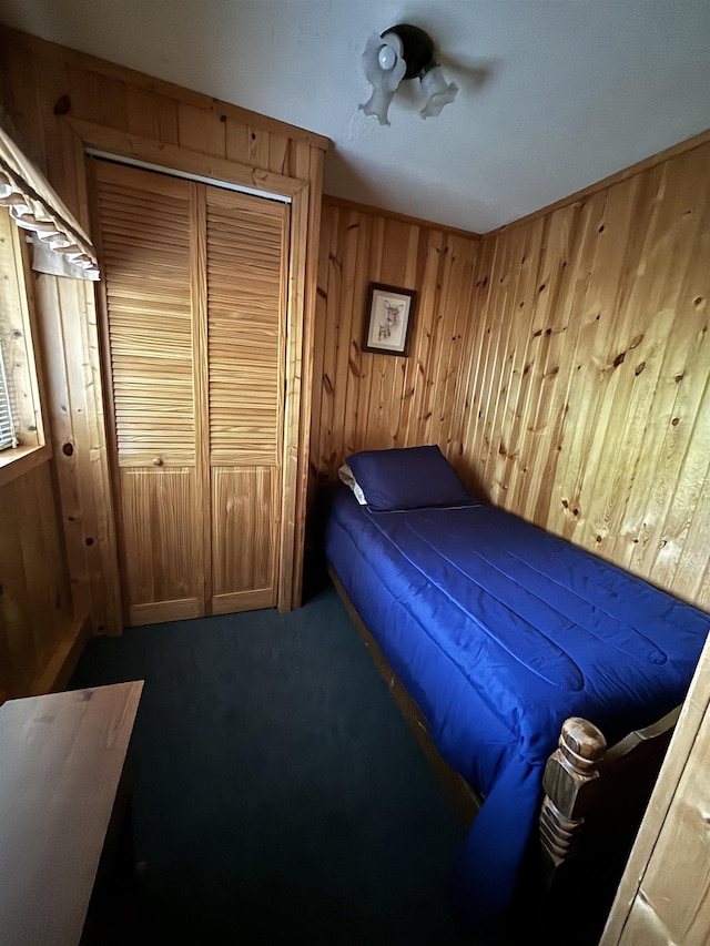 carpeted bedroom with wooden walls and a closet