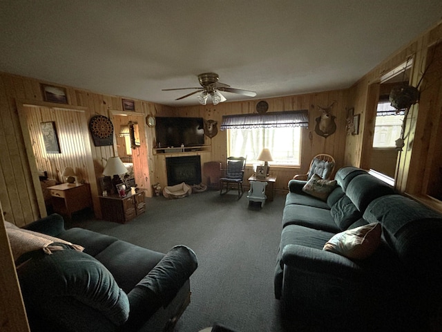 carpeted living room featuring ceiling fan and wooden walls