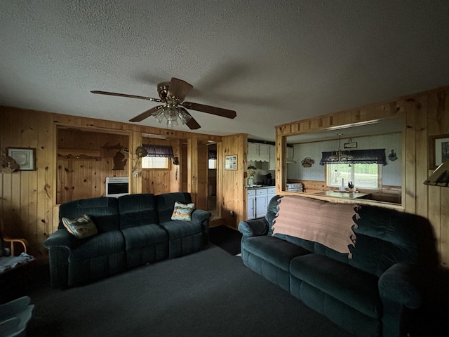 living room with ceiling fan, carpet, a textured ceiling, and wood walls