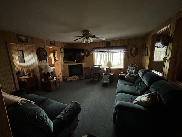 living room with wooden walls, ceiling fan, and carpet flooring