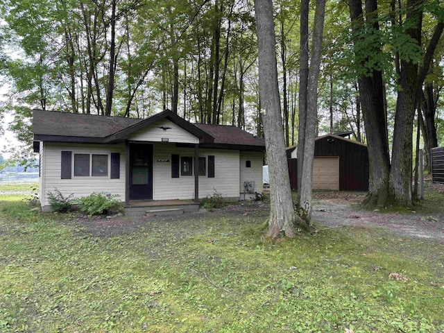 view of front of property featuring a garage, an outdoor structure, and a front lawn