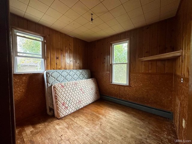 unfurnished bedroom featuring wood walls and a baseboard heating unit