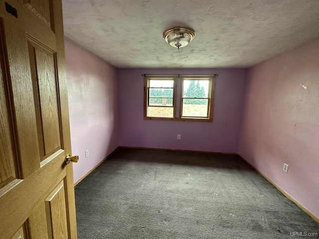 empty room featuring dark colored carpet and a textured ceiling