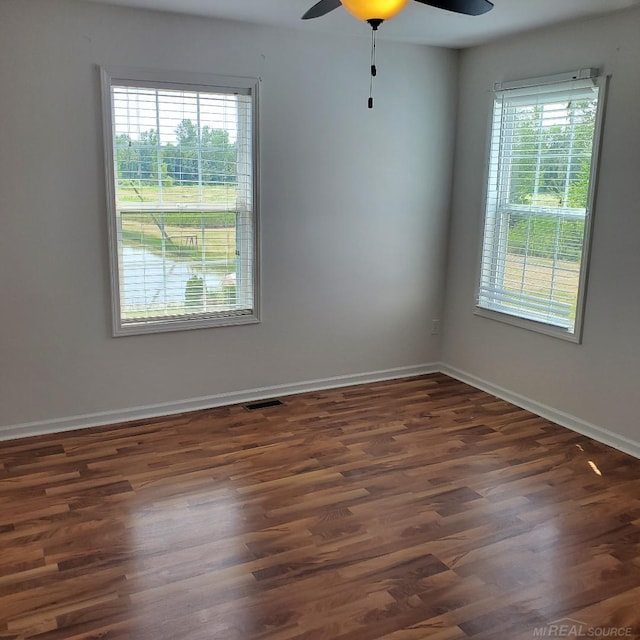 spare room featuring a wealth of natural light, dark wood-style flooring, and baseboards