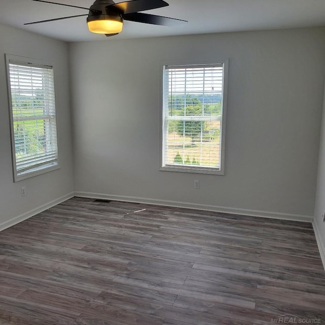 spare room with dark wood finished floors, baseboards, and ceiling fan