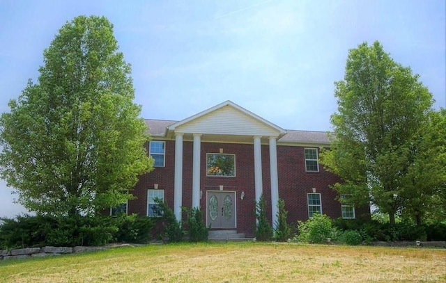 greek revival house with brick siding and a front lawn