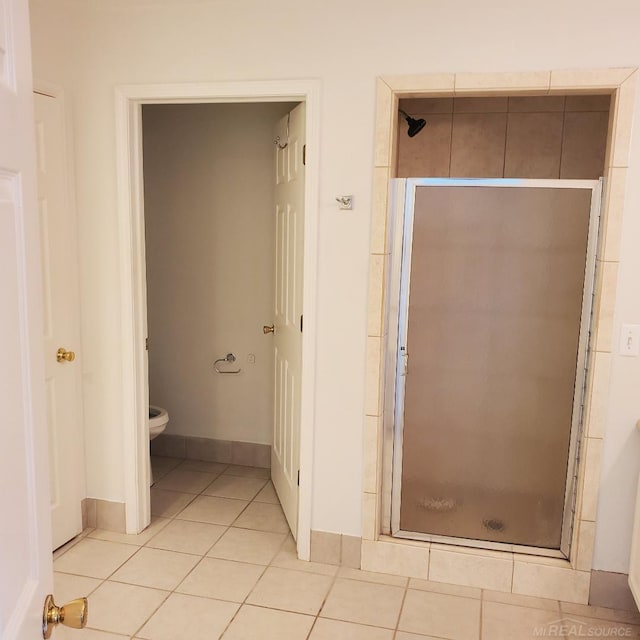 bathroom with toilet, a shower stall, baseboards, and tile patterned floors