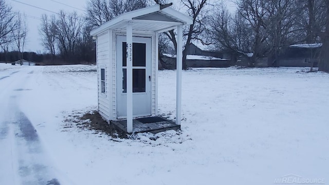 snow covered structure featuring a shed