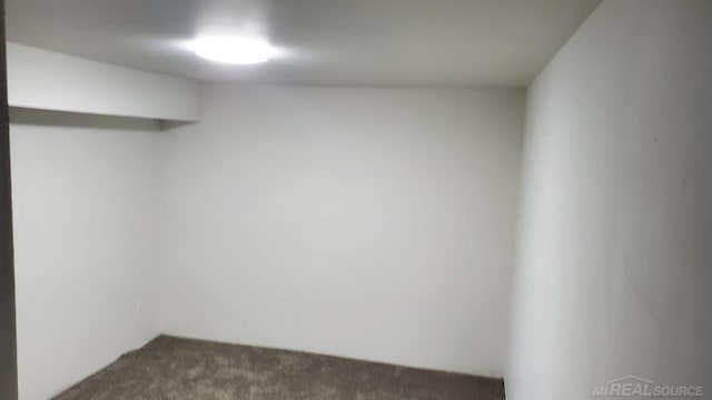 spare room with dark colored carpet