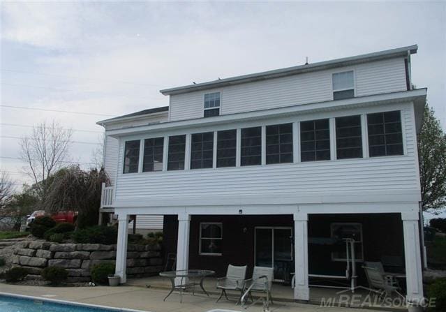 back of property featuring an outdoor pool and a patio