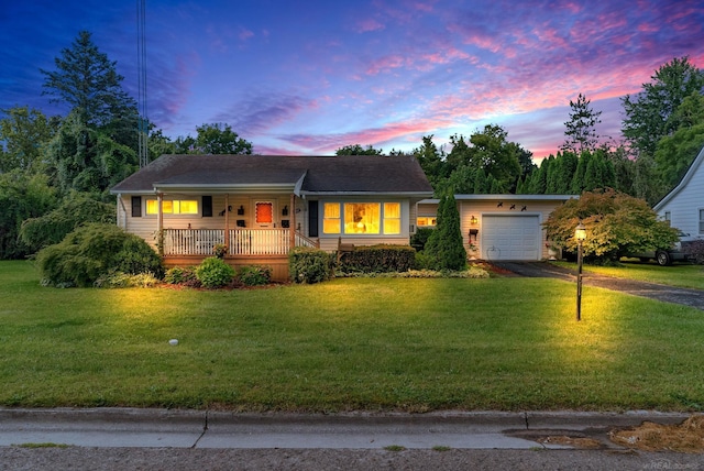 ranch-style house with a garage, covered porch, and a lawn