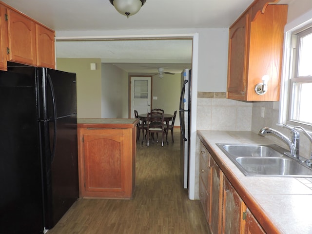 kitchen with stainless steel fridge, black fridge, decorative backsplash, ceiling fan, and wood-type flooring