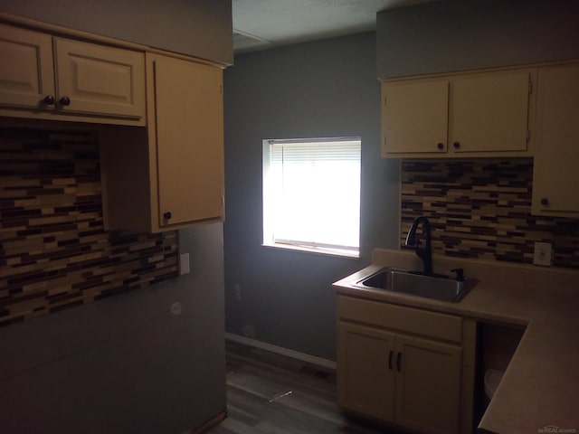 kitchen with tasteful backsplash, cream cabinets, sink, and dark hardwood / wood-style flooring