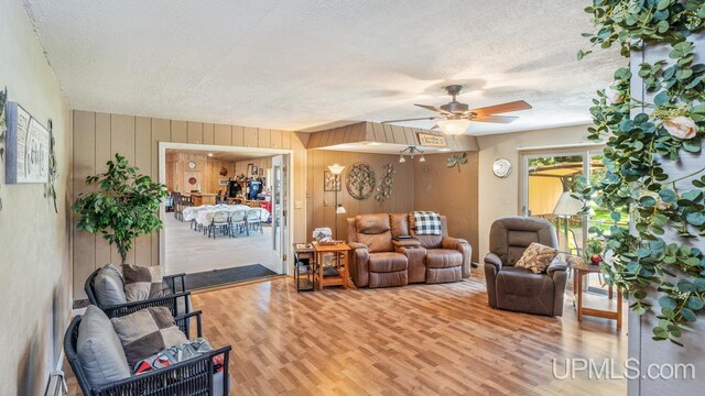 living room featuring a baseboard radiator, a textured ceiling, ceiling fan, and wood-type flooring