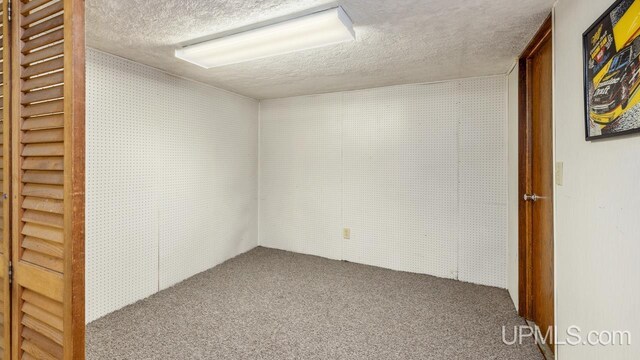 carpeted empty room with a textured ceiling