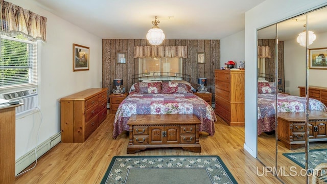 bedroom featuring a closet, baseboard heating, cooling unit, and light hardwood / wood-style floors