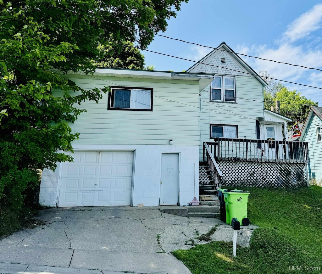 view of front facade with a wooden deck, a garage, and a front yard