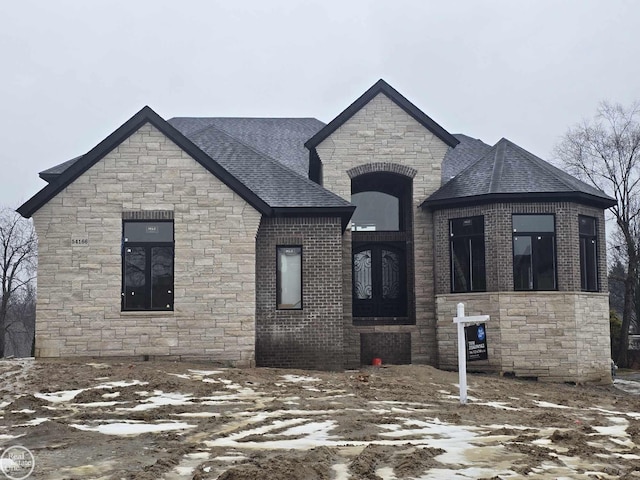 view of front of house with roof with shingles and brick siding