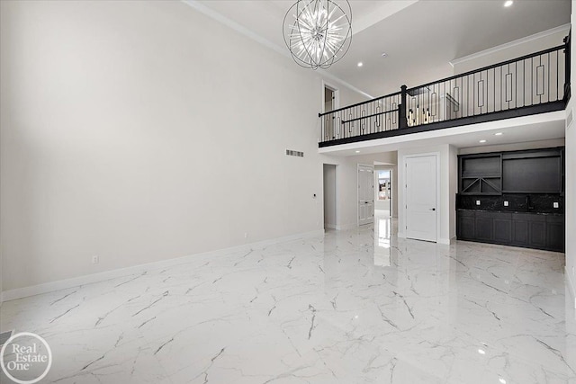 unfurnished living room with an inviting chandelier, ornamental molding, and a high ceiling