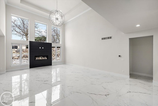 foyer entrance featuring an inviting chandelier, a towering ceiling, and a tray ceiling