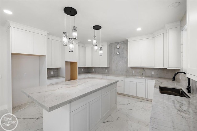 kitchen with marble finish floor, a sink, white cabinetry, and light stone countertops