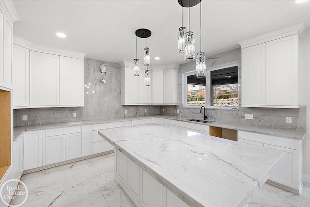 kitchen with marble finish floor, tasteful backsplash, white cabinetry, and a sink