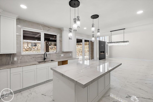 kitchen featuring marble finish floor, backsplash, a sink, and recessed lighting