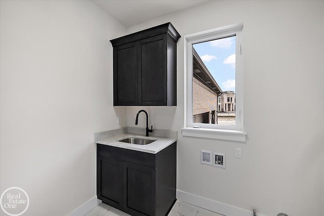 interior space with hookup for a washing machine, a sink, baseboards, marble finish floor, and cabinet space