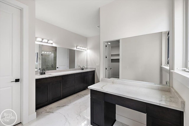 bathroom featuring a stall shower, marble finish floor, a sink, and double vanity