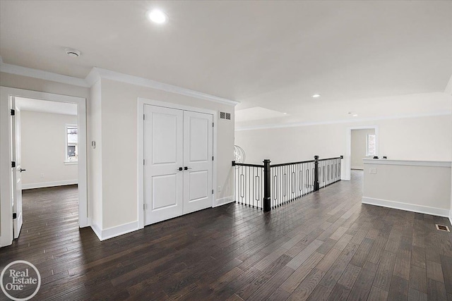 corridor with recessed lighting, dark wood-style flooring, visible vents, baseboards, and ornamental molding