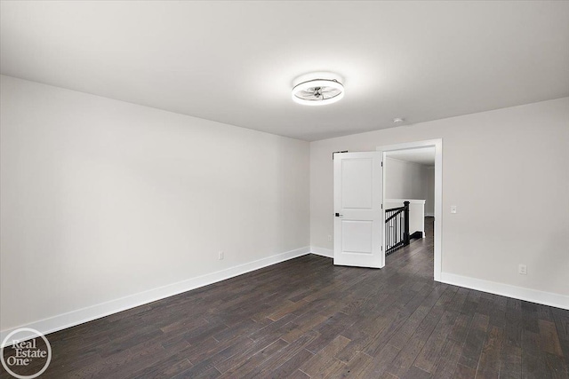 spare room featuring dark wood-style floors and baseboards